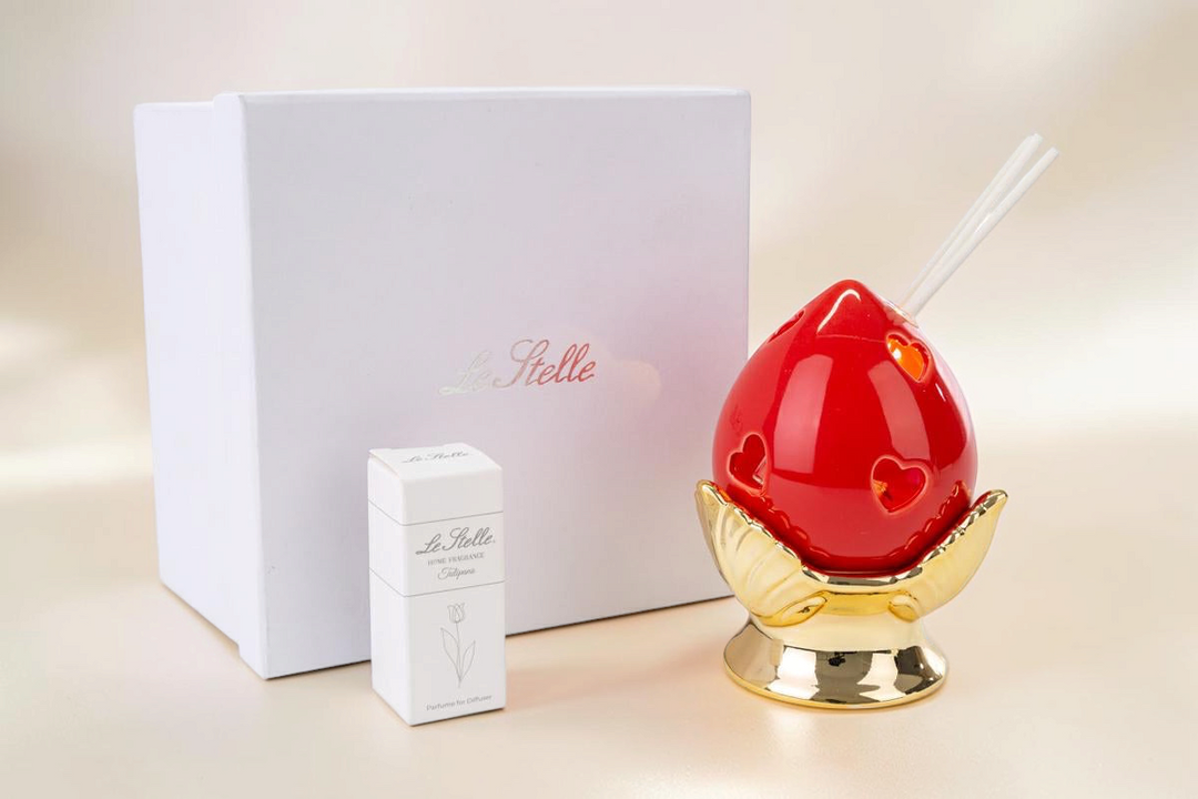 Profumatore La Festa Perfetta a forma di pomo rosso in porcellana con base dorata e bastoncini, incluso astuccio.