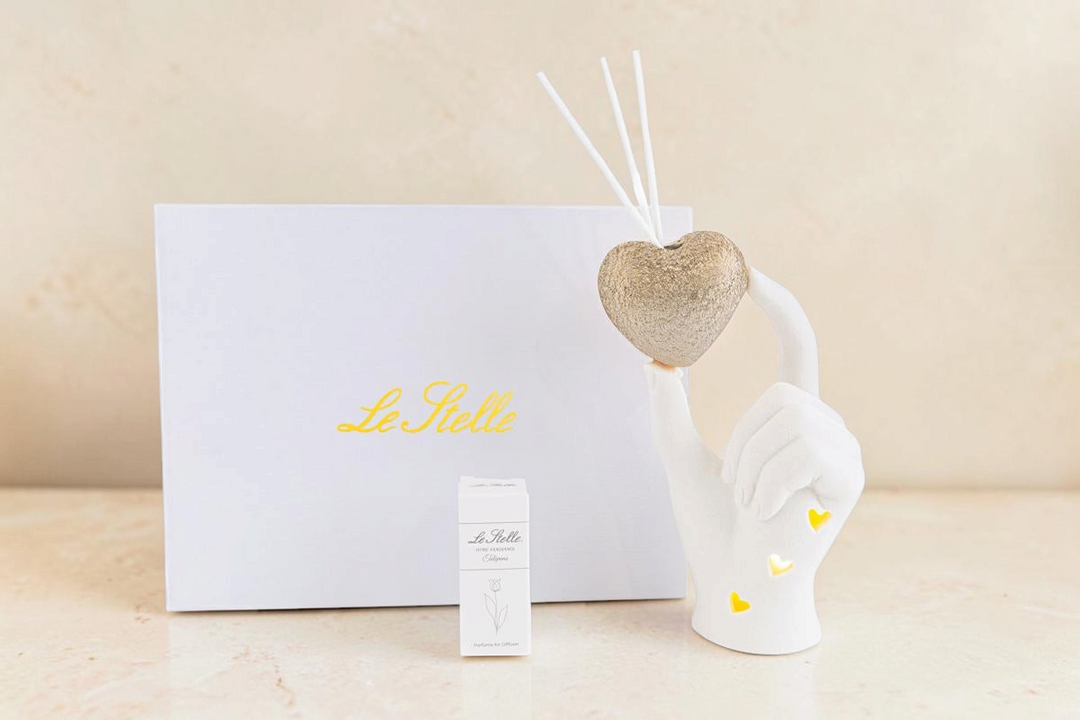 Profumatore La Festa Perfetta a forma di mano bianca che regge un cuore dorato con LED e bastoncini diffusori