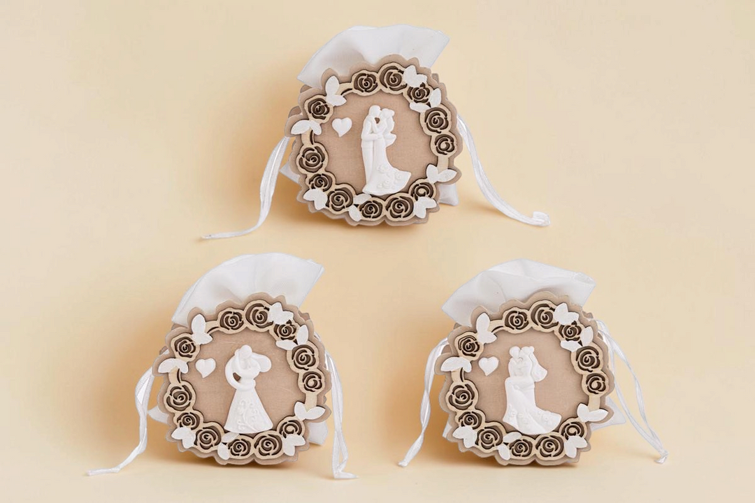 Tre sacchetti portaconfetti La Festa Perfetta in legno con decorazioni a tema sposi, rose e farfalle bianche