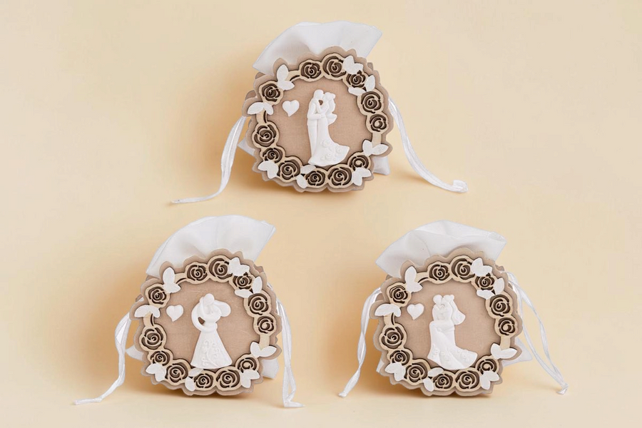 Tre sacchetti portaconfetti La Festa Perfetta in legno con decorazioni a tema sposi, rose e farfalle bianche