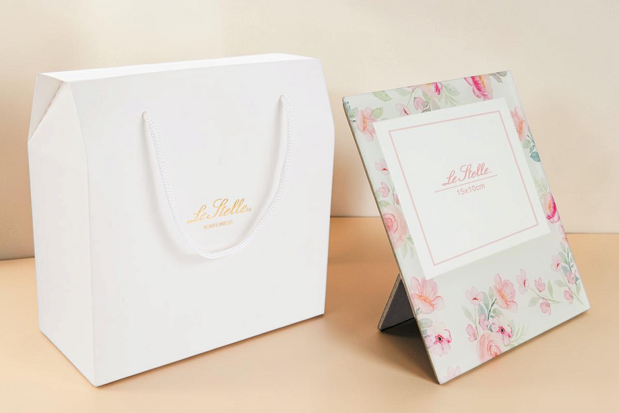 Cornice portafoto in vetro La Festa Perfetta con decoro floreale rosa e shopper regalo bianca coordinata